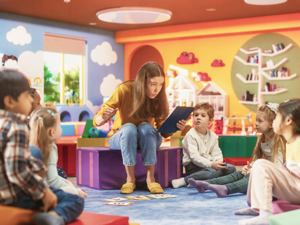 Ausbildung im Kita-Werk / eine Erzieherin liest den Kindern vor