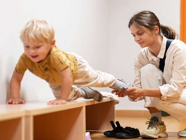 Mutter hilft Kindergarten-Kind beim Anziehen